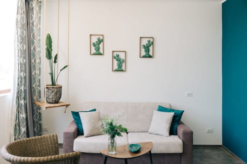 Moderna lounge di Tenuta Fascianello a Fasano con divano grigio, accenti turchesi, pianta pensile e arte murale con cactus