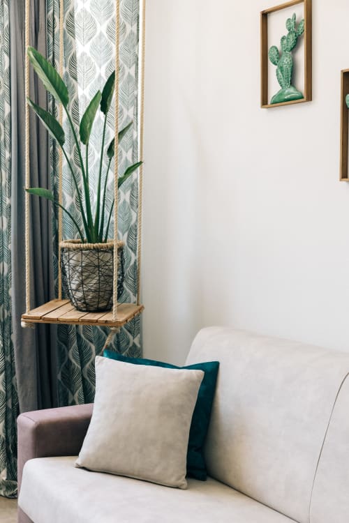 Elegante angolo camera da letto a Tenuta Fascianello con divano bianco, tende botaniche, pianta in vaso e quadri con cactus
