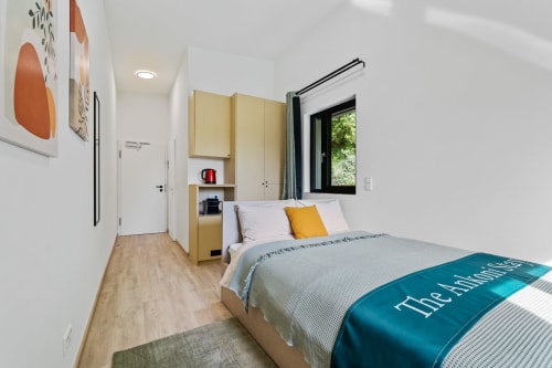 Chambre moderne à Mattbnb Ankoni Stay à Metz avec lit, meuble de rangement jaune, fenêtre et vue sur la ville