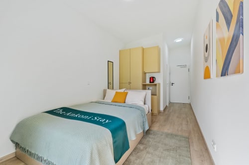 Chambre moderne à Mattbnb Metz avec lit, armoire jaune, vue sur la ville, TV écran plat et œuvres d'art contemporain