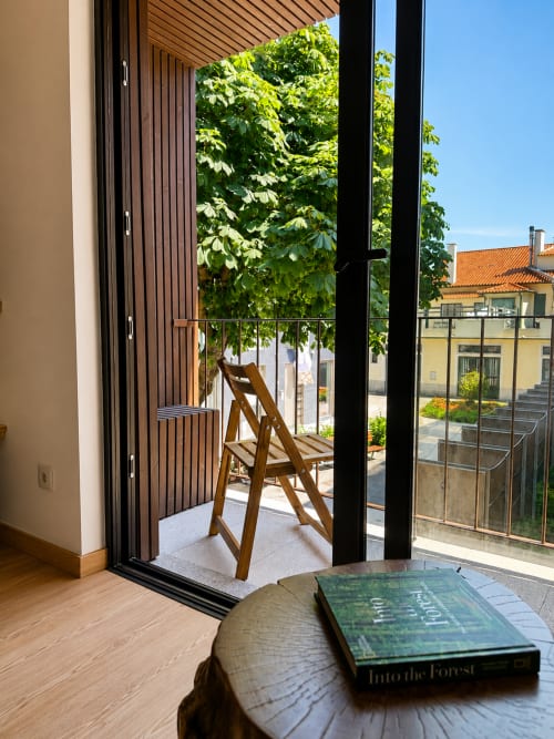 Apartamento com terraço em Terra Clara Studios em Esposende com cadeira de madeira, vista da cidade e varanda com vegetação luxuriante