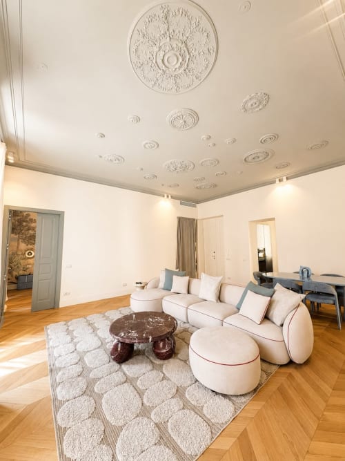 Area living della Suite Ingrid alle SEVEN SUITES SANREMO con divano curvo, tavolo in marmo, soffitto ornato, pavimento in parquet e vista sulla città