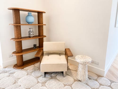 Elegante zona soggiorno nella Suite Ingrid di Seven Suites Sanremo con poltrona color crema, scaffali in legno e tavolino a righe