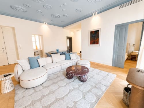 Soggiorno moderno nella Suite Ingrid dei Seven Suites Sanremo con divano bianco curvo, tavolino in marmo e pavimenti in legno