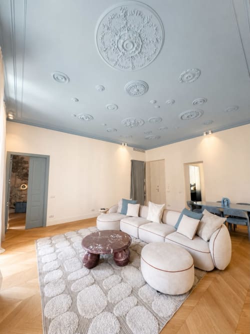 Soggiorno Suite Ingrid ai Seven Suites Sanremo con divano color crema, tavolo in marmo, medaglioni decorativi al soffitto e legno duro