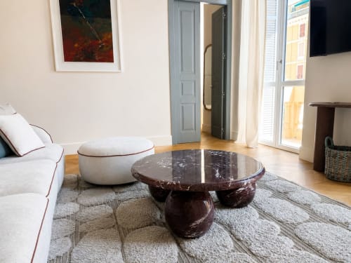 Soggiorno di suite moderna con tavolo in marmo, pouf bianco e vista sulla città presso Seven Suites Sanremo