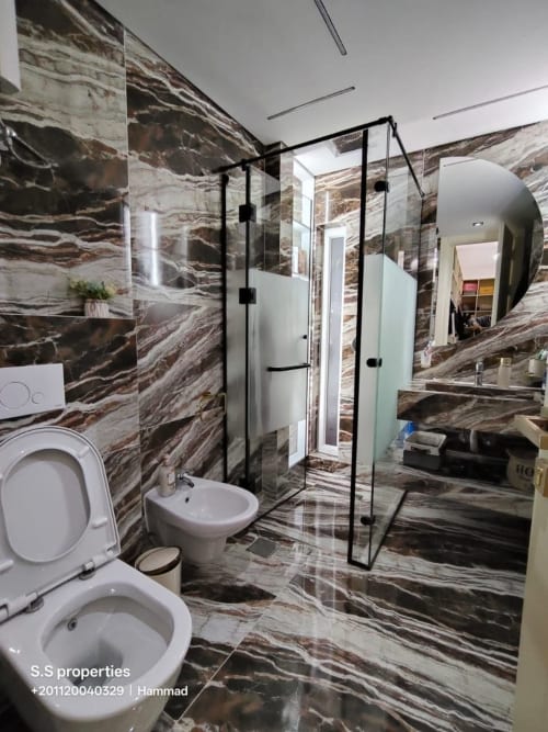 Bagno moderno con pareti in marmo, cabina doccia in vetro, doppi lavandini e servizi accessibili alla Gold Suite Sharm el Sheikh