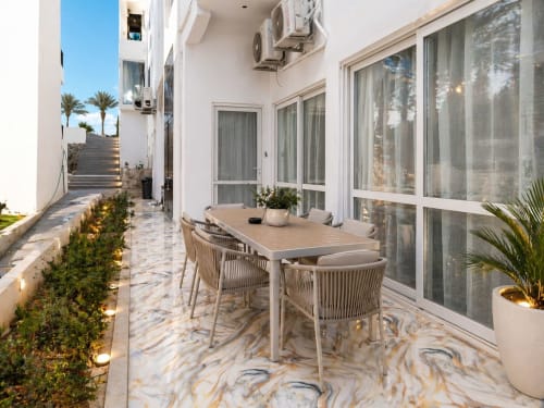 Elegante zona pranzo in terrazza dell'Apartment Gold a Sharm El Sheikh con pavimenti in marmo e ampie finestre