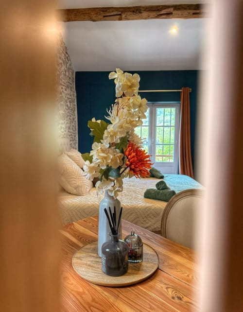 Chambre élégante de la Bastide la Mourelette avec fleurs fraîches, mur d'accent foncé et poutres en bois rustique à Toulon