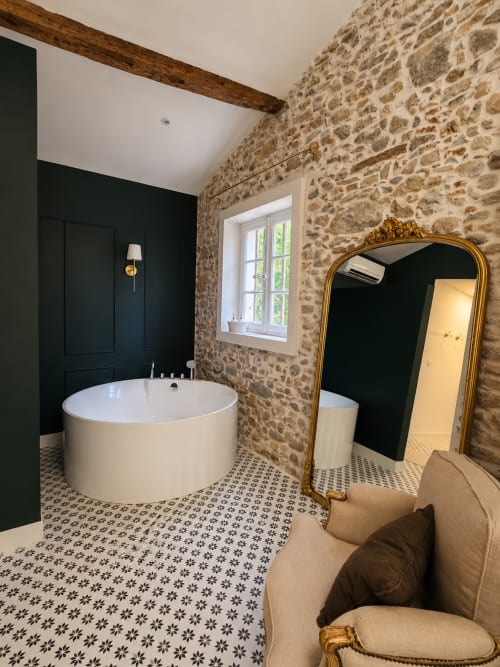 Salle de bain luxueuse à la Bastide la Mourelette Toulon avec baignoire ronde, murs en pierre et miroir doré