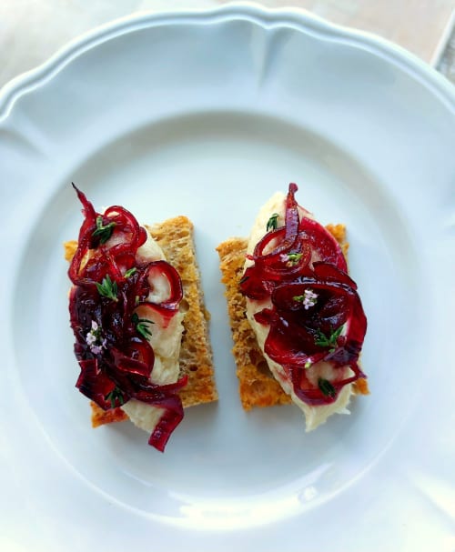 Elegante antipasto gourmet da Aura Relais: crostini croccanti con crema, barbabietole arrostite ed erbe fresche su piatto bianco