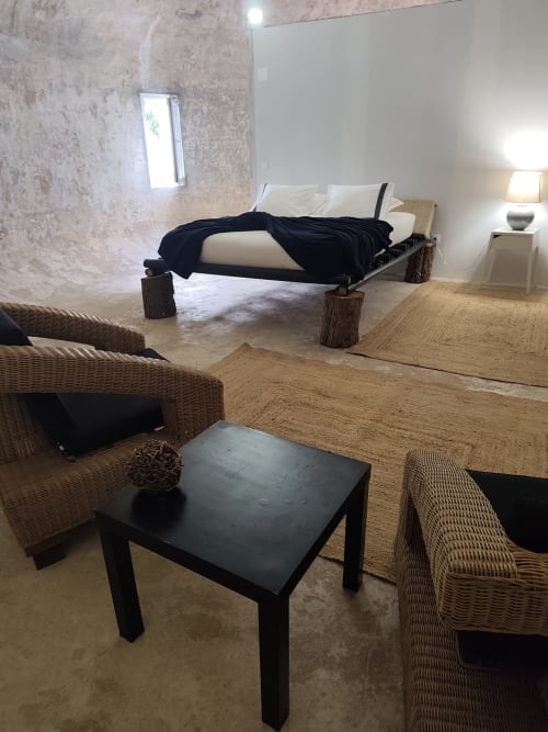 Interior rústico da pousada Bagos do Vilar com mobiliário de vime, mesa preta e cama com estrutura de troncos em Vilar, Portugal