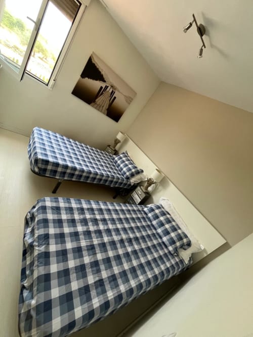 Dormitorio con dos camas individuales de ropa de cama a cuadros azules en apartamento Sant Jordi con vistas al jardín, cerca de la playa y campo de golf