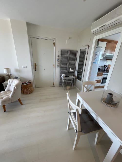 Moderno salón con comedor, muebles blancos, cocina abierta, aire acondicionado y piso de madera clara