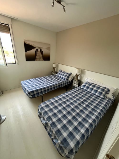 Dormitorio doble con ropa de cama a cuadros azules en el apartamento Sant Jordi cerca de la playa y el campo de golf