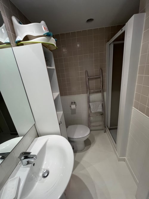 Baño moderno del apartamento Sant Jordi con lavabo blanco, inodoro, cabina de ducha y toallero calefactor