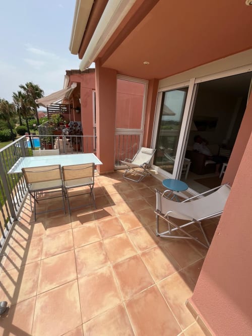 Amplia terraza de terracota con asientos, vistas al golf y acceso al apartamento Sant Jordi cerca de la playa