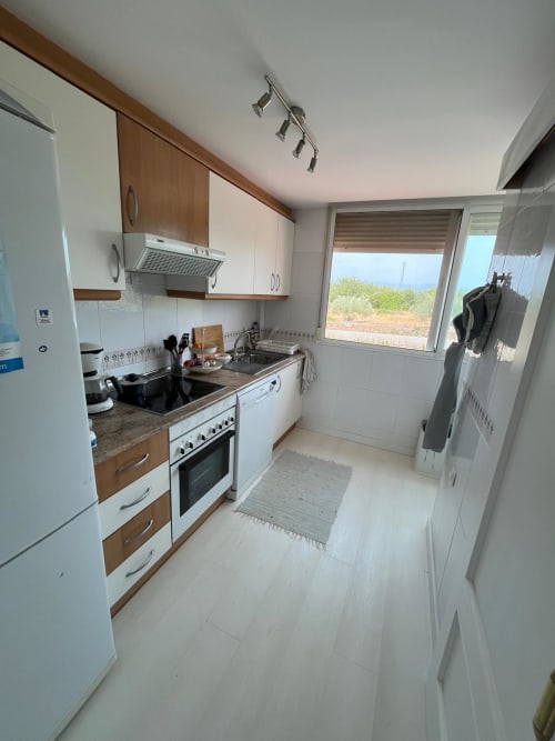 Cocina moderna con muebles de madera y blanco, electrodomésticos de acero inoxidable, con vistas al campo de golf