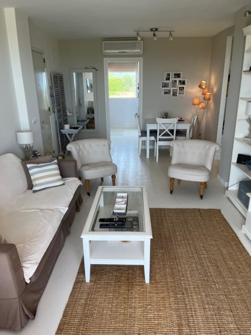 Moderna sala de estar con asientos, mesa blanca y vistas al campo de golf y jardín en Sant Jordi