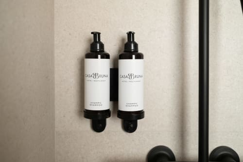 Dos dispensadores de champú Casa Bruna montados en la pared de baño beige del Hotel Bruna en Esterri D'Àneu