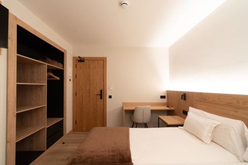 Moderno dormitorio doble en Hotel Bruna de Esterri D'Àneu con mobiliario de madera, zona de trabajo y vestidor