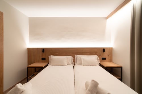 Moderna habitación doble del Hotel Bruna en Esterri D'Àneu con camas gemelas, cabecero de madera y diseño minimalista de iluminación