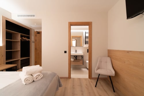 Moderno dormitorio de hotel en Hotel Bruna con muebles de madera, baño privado y comodidades que incluyen TV y calefacción