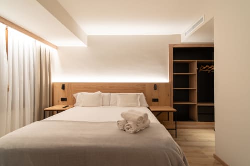 Moderno dormitorio doble en Hotel Bruna con cabecero de madera, ropa de cama blanca, armario empotrado e iluminación ambiental en Esterri