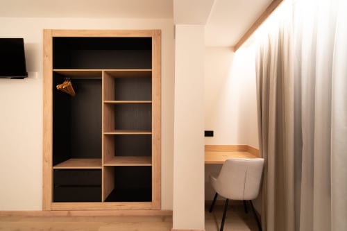 Moderno armario de habitación de hotel con estructura de madera, estanterías y área de escritorio en Hotel Bruna, Esterri D'Àneu