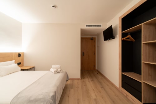 Habitación moderna del Hotel Bruna en Esterri D'Àneu con cama, TV, armario de madera y suelo de madera