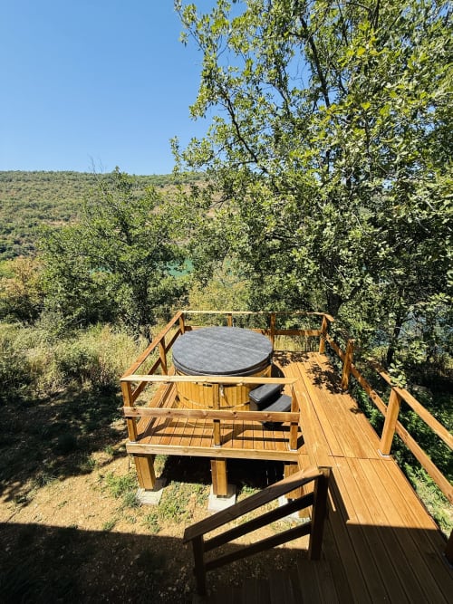 Terrasse bois avec bain à remous surplombant les montagnes et la rivière aux Cabanes et lodges du Belvédère, Serrières-sur-Ain