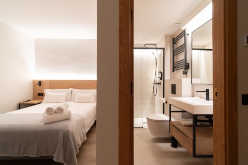 Habitación moderna del Hotel Bruna con cama y baño privado con ducha y detalles de madera
