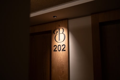 Placa de puerta iluminada de la habitación 202 del Hotel Bruna en Esterri d'Àneu con inicial decorativa B y número