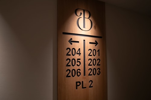 Placa direccional del Hotel Bruna indicando habitaciones 201-206 y PL 2 en tablero de madera