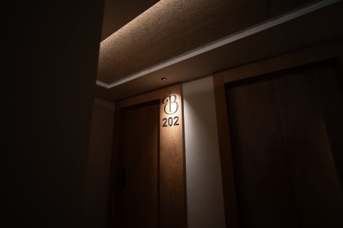 Entrada a la habitación 202 del Hotel Bruna con puerta de madera y placa luminosa del número de habitación en Esterri d'Àneu