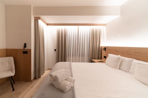 Habitación moderna del Hotel Bruna en Esterri D'Àneu con cama queen, muebles de madera y cortinas del piso al techo.