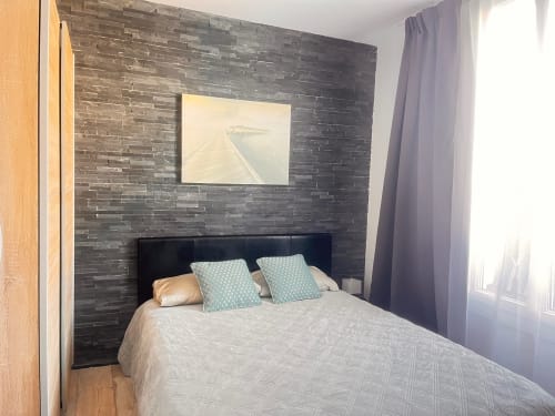 Chambre moderne à La Villa L'Oiseau Bleu Resort à Blonville-sur-Mer avec mur en briques foncées, lit queen-size et écran plat