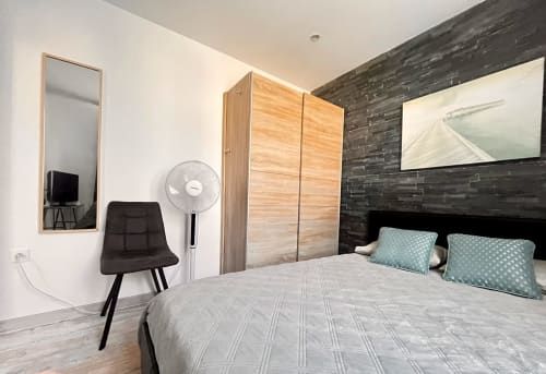 Chambre moderne à La Villa L'Oiseau Bleu à Blonville-sur-Mer avec lit, armoire en bois et mur d'accent en brique foncée