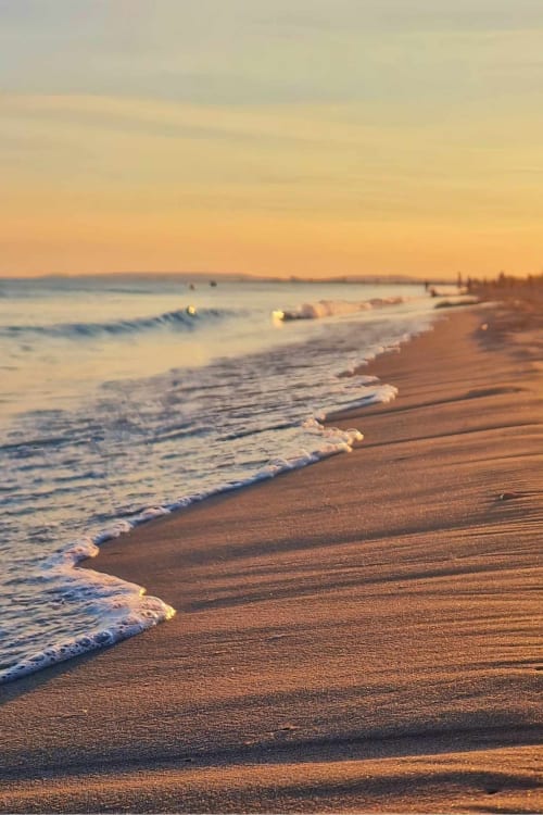 Coucher de soleil doré sur les vagues de la plage de Sable & Pampas à Carnon-Plage, rivage sablonneux baigné de lumière vespérale