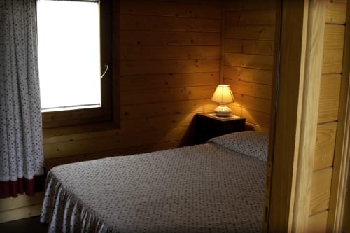 Accogliente camera da letto in legno presso Country House Bosco d'Olmi con letto, lampada e finestra con vista sul giardino