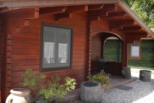 Casa Volpe apartment exterior with red wooden log walls, covered patio, garden seating, and stone pathway at Country House