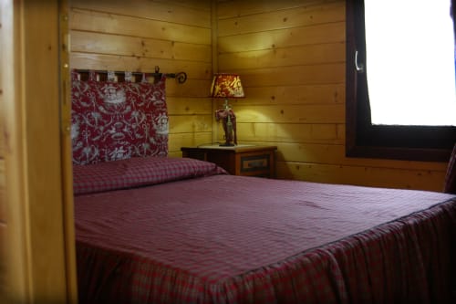 Cozy wooden bedroom with red bedding at Country House Bosco d'Olmi, featuring bedside lamp and garden views
