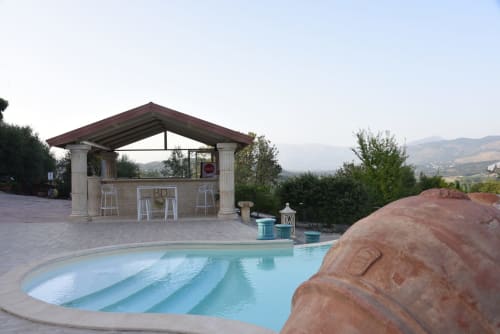 Luxurious poolside terrace at Casa Volpe with stone bar pavilion, blue infinity pool, and mountain views in Lazio, Italy