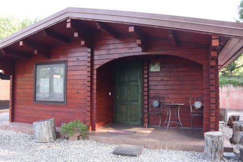 Red log cabin Casa Volpe at Country House Bosco d'Olmi with green door, patio furniture, and garden views in Sant'Andrea del