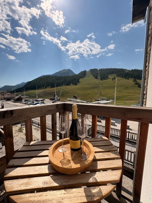 Balcon avec vue montagne aux Tanières de Montgenèvre, champagne et verres face aux pics alpins