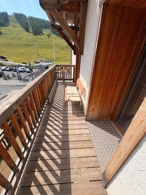 Balcon en bois avec vue sur les montagnes aux Tanières de Montgenèvre, chaises et paysage alpin avec station de ski