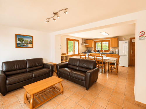 Open-plan living and kitchen area at Casa Emilia villa in Moraira with brown leather sofas, wooden table, and modern wood
