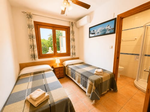 Twin bedroom with wooden beds, terracotta tiles, and en-suite bathroom at Casa Emilia villa in Moraira