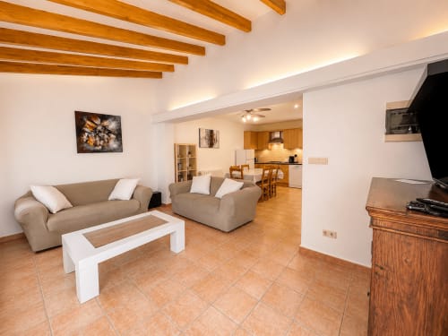 Spacious living room in Casa Emilia villa, Moraira with beige sofas, wooden beams, and open-plan kitchen layout
