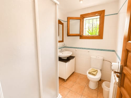 Bright bathroom in Casa Emilia villa, Moraira featuring white tile walls, terracotta floor, wooden framed mirror, sink, and